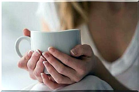 Woman holding a cup of tea as a treatment for sore throat