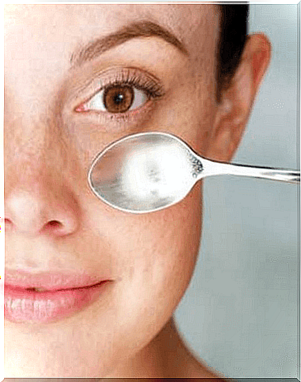 Woman holding a spoon under her eye