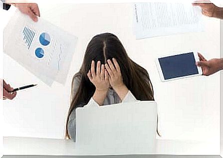 Woman hiding face behind hands pointing fingers at office