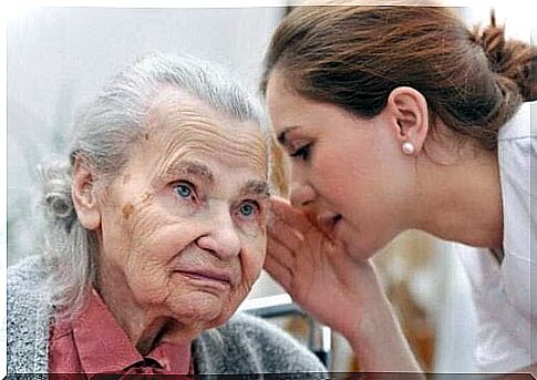 Woman whispers to elderly woman with hearing loss