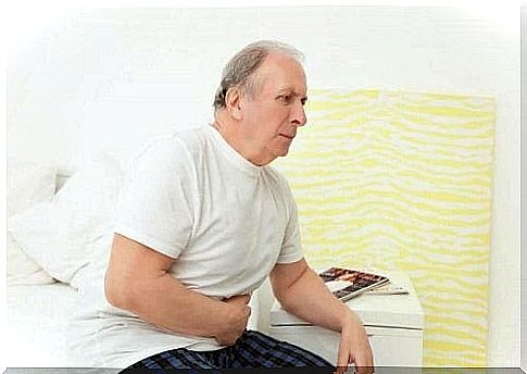 Elderly man sitting on edge of bed in pain 