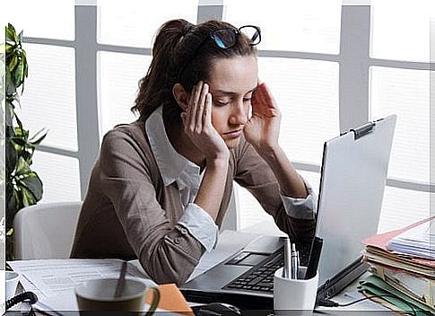 Woman sitting with her hands on her head in front of the computer