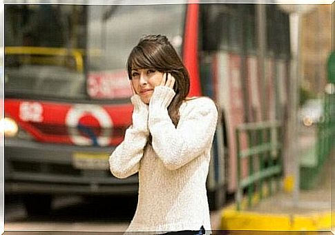 Woman by noisy vehicles covering her ears