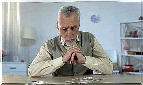 An elderly man focusing on the pieces of a puzzle